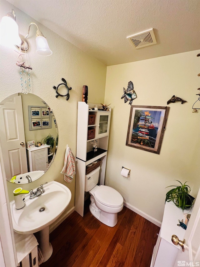 bathroom featuring a textured ceiling, toilet, and hardwood / wood-style flooring