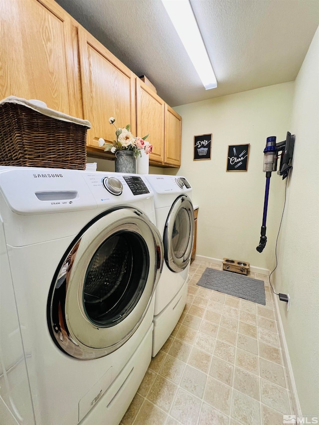 laundry area with cabinets, a textured ceiling, and washing machine and dryer