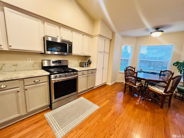 kitchen featuring light stone countertops, light wood-type flooring, and appliances with stainless steel finishes