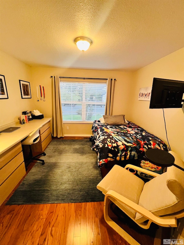 bedroom with a textured ceiling and dark hardwood / wood-style floors