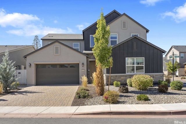 view of front facade featuring stone siding, decorative driveway, stucco siding, and an attached garage