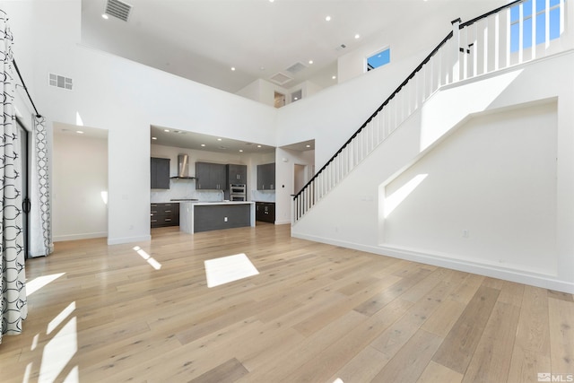 unfurnished living room with a high ceiling and light wood-type flooring