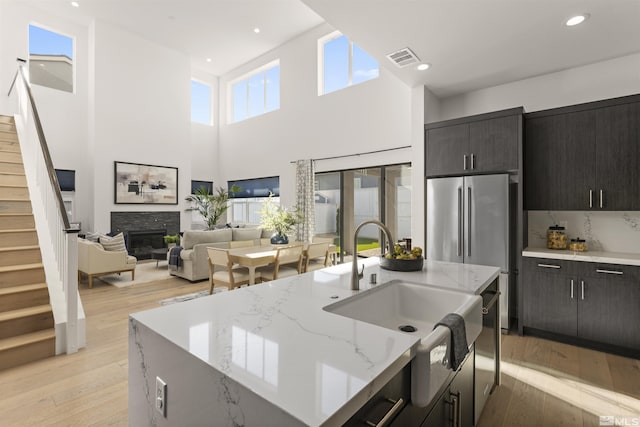 kitchen with open floor plan, light wood-style flooring, a sink, and a stone fireplace
