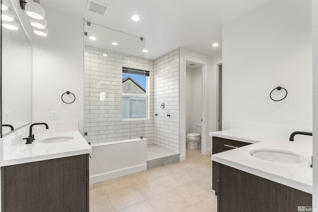 bathroom featuring vanity, tile patterned flooring, toilet, and tiled shower