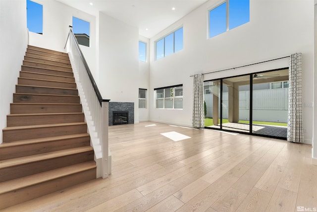 unfurnished living room with a towering ceiling and light wood-type flooring