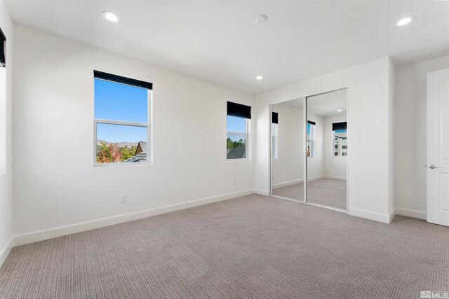 unfurnished bedroom with light carpet, a closet, and multiple windows