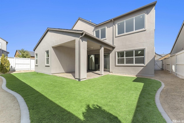 back of house featuring a fenced backyard, a lawn, stucco siding, and a patio