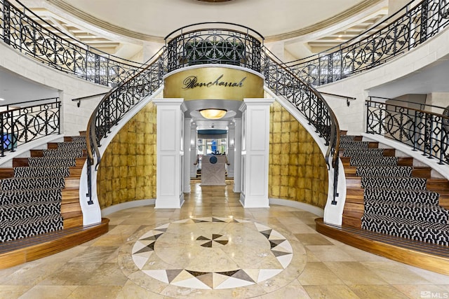 foyer featuring decorative columns, a high ceiling, arched walkways, and stairway