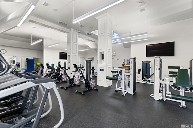 gym featuring ornate columns, a high ceiling, and visible vents