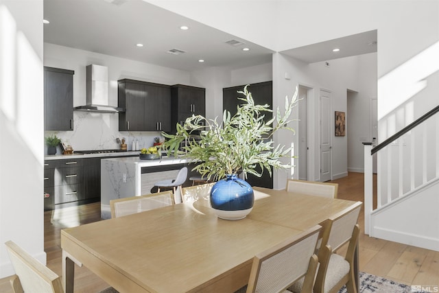 dining area featuring light wood-style floors, recessed lighting, visible vents, and stairway