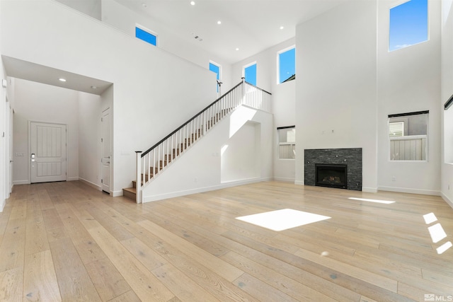 unfurnished living room with a high ceiling, a fireplace, and light hardwood / wood-style flooring