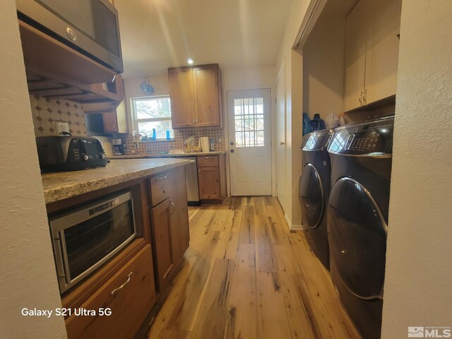 laundry area featuring cabinets, washing machine and dryer, and light hardwood / wood-style flooring