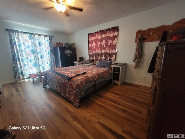 bedroom with ceiling fan, a textured ceiling, and dark hardwood / wood-style floors