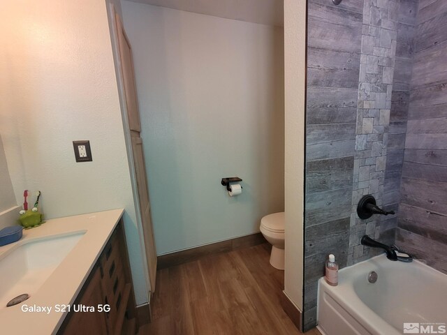 full bathroom with toilet, vanity, hardwood / wood-style floors, and tiled shower / bath