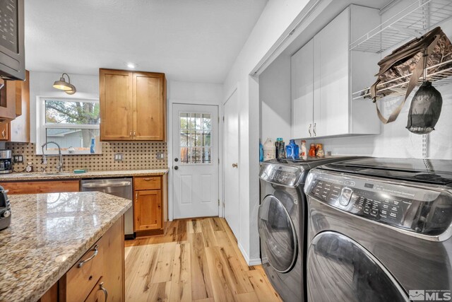 washroom with light wood-type flooring, washing machine and dryer, and sink