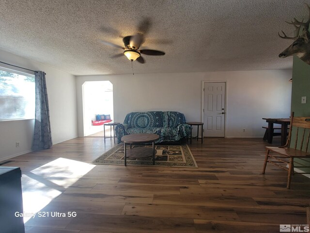 living area featuring a textured ceiling, dark hardwood / wood-style floors, and ceiling fan