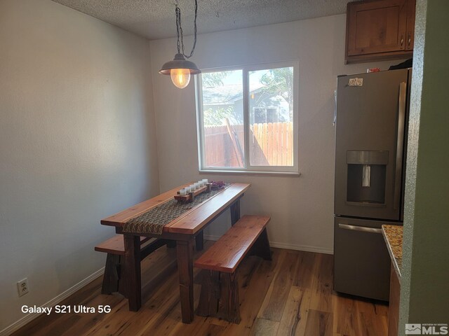 dining room featuring light wood-type flooring and a textured ceiling