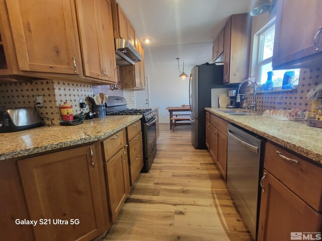 kitchen featuring light hardwood / wood-style floors, sink, backsplash, extractor fan, and appliances with stainless steel finishes