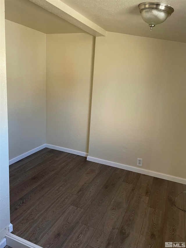 spare room with a textured ceiling and dark wood-type flooring