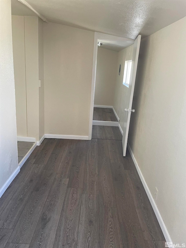 hall with a textured ceiling and dark hardwood / wood-style floors