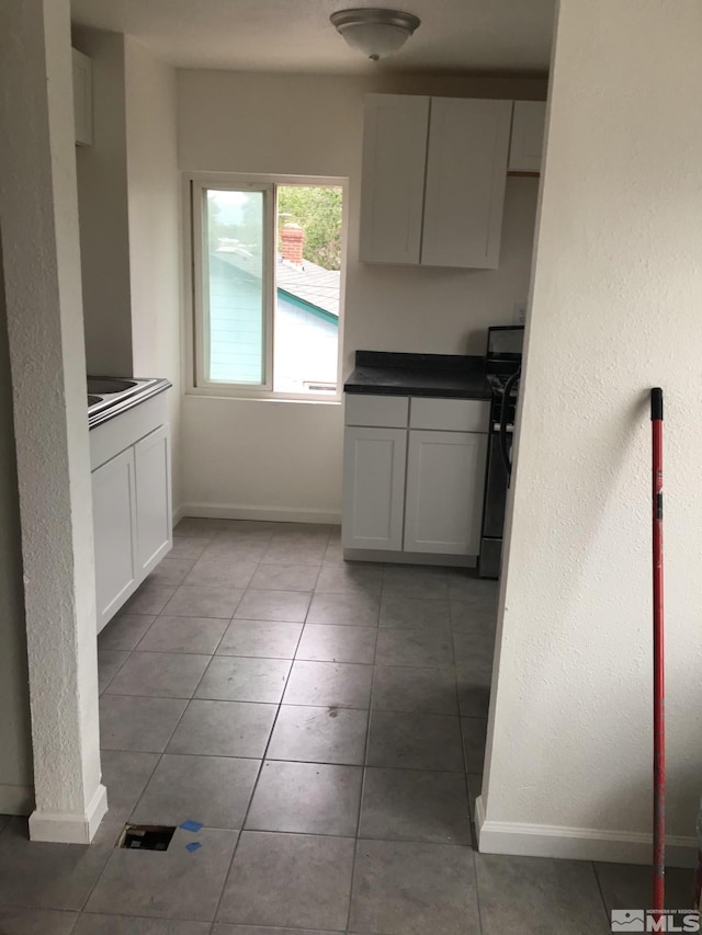 kitchen with tile patterned flooring, white cabinetry, and black range with electric stovetop