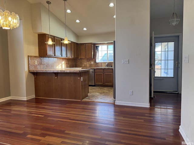 kitchen featuring decorative backsplash, dark hardwood / wood-style flooring, kitchen peninsula, and a breakfast bar