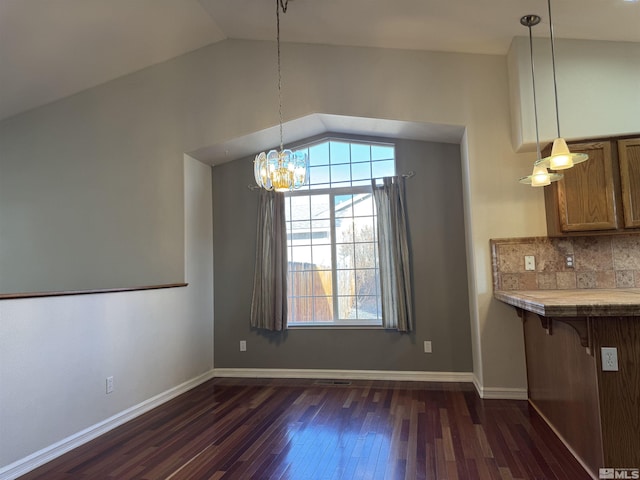 unfurnished dining area with dark hardwood / wood-style floors, vaulted ceiling, and an inviting chandelier