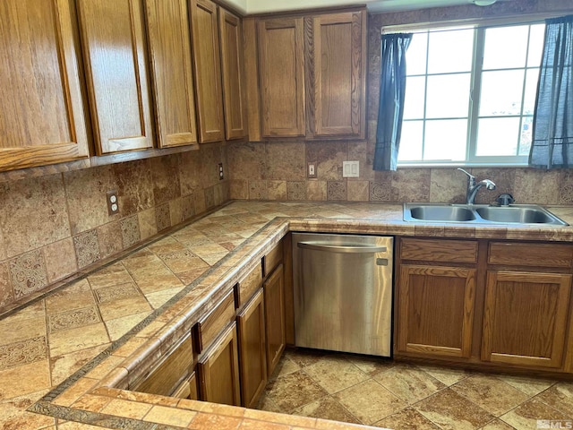 kitchen with tile countertops, dishwasher, sink, and tasteful backsplash