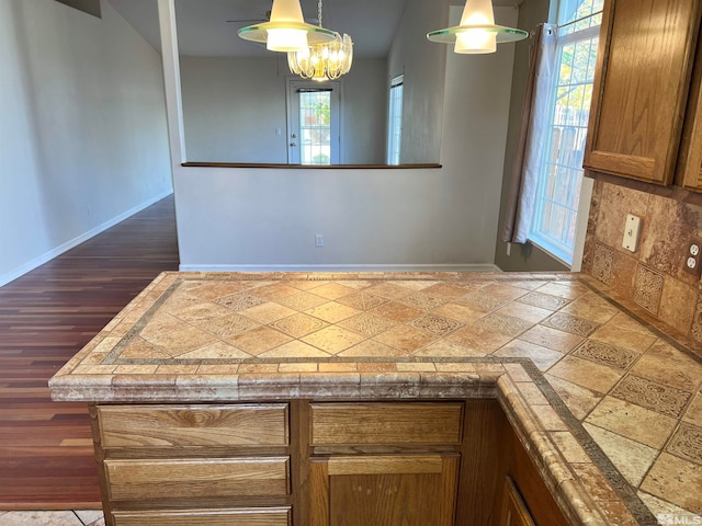 kitchen with decorative light fixtures, a healthy amount of sunlight, an inviting chandelier, and tasteful backsplash