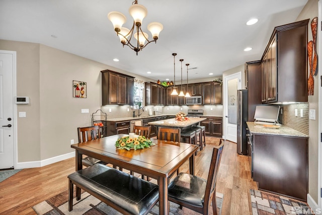 dining room featuring an inviting chandelier, sink, and light hardwood / wood-style flooring