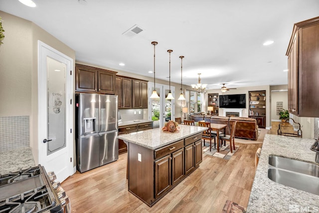 kitchen with hanging light fixtures, a kitchen island, appliances with stainless steel finishes, light hardwood / wood-style floors, and decorative backsplash