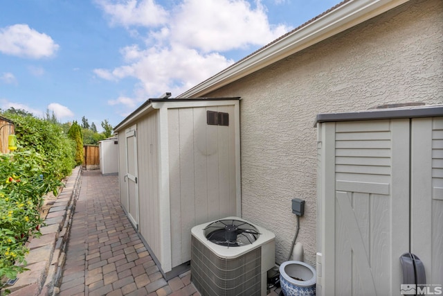 view of side of home featuring a shed, a patio area, and central air condition unit