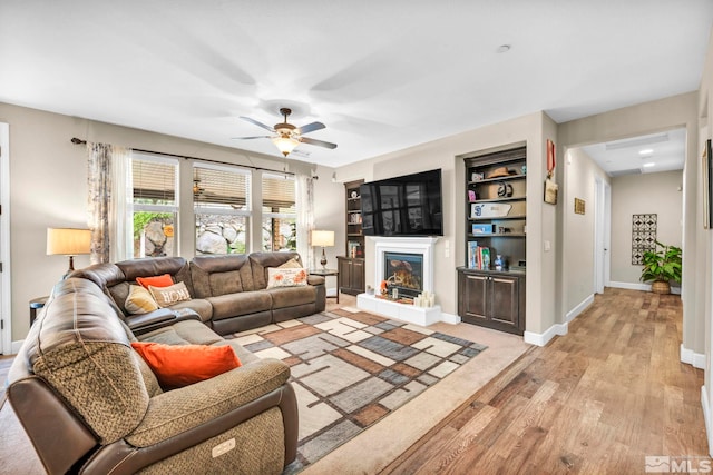 living room featuring ceiling fan, built in features, and light hardwood / wood-style floors