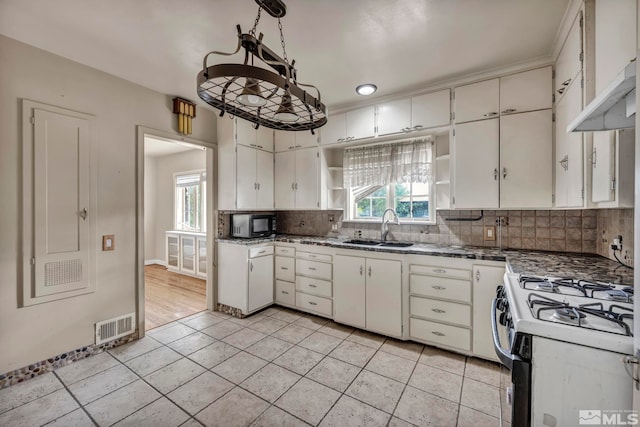 kitchen featuring white cabinets, tasteful backsplash, gas range gas stove, light tile patterned floors, and sink