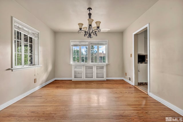 unfurnished dining area featuring light wood-type flooring and a chandelier