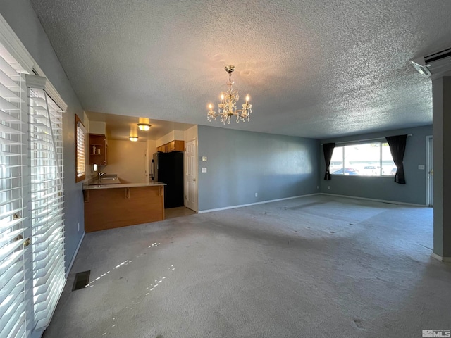 unfurnished living room with a textured ceiling, an inviting chandelier, and light carpet