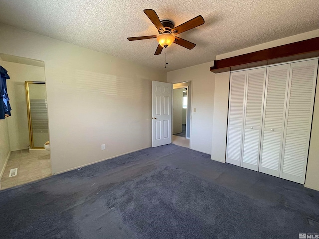 unfurnished bedroom featuring ceiling fan, a textured ceiling, a closet, and dark colored carpet