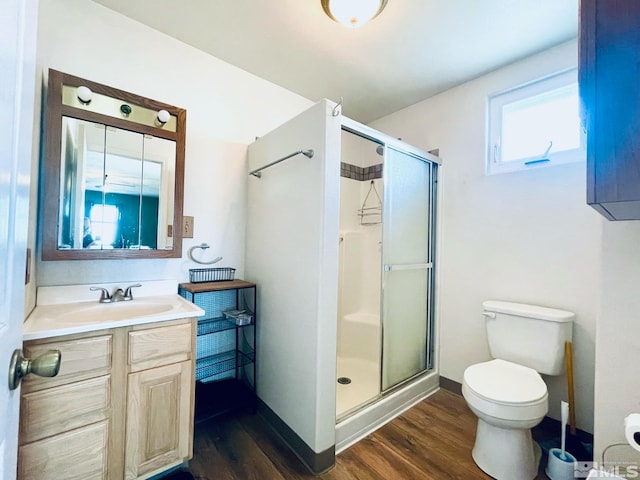 bathroom with hardwood / wood-style floors, a shower with door, vanity, and toilet