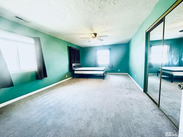 unfurnished bedroom with a closet, carpet, ceiling fan, and a textured ceiling