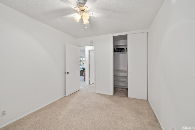 unfurnished bedroom featuring a textured ceiling, light carpet, ceiling fan, and a closet