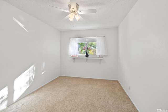 spare room featuring light carpet, a textured ceiling, and ceiling fan