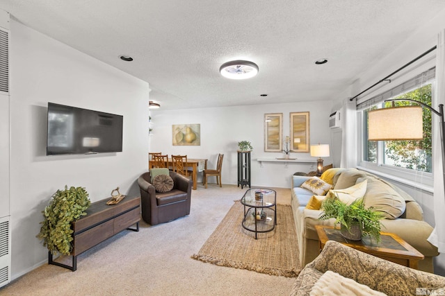 living room featuring light carpet, an AC wall unit, and a textured ceiling