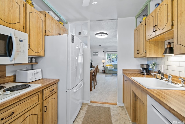 kitchen with a textured ceiling, backsplash, sink, and white appliances