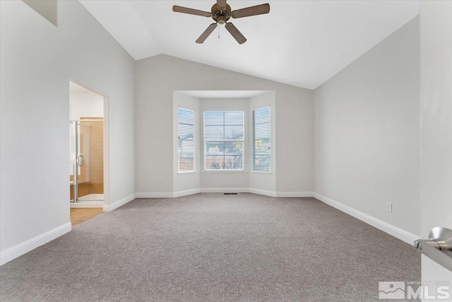 empty room with ceiling fan, vaulted ceiling, and light colored carpet