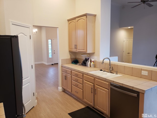 kitchen with light brown cabinets, sink, dishwasher, tile counters, and black refrigerator