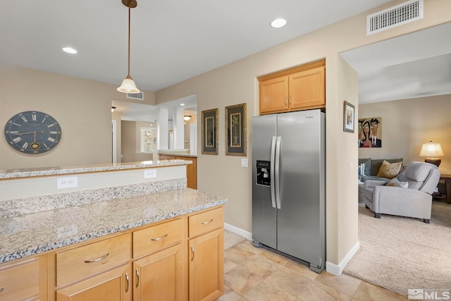 kitchen with light stone counters, decorative light fixtures, stainless steel fridge with ice dispenser, light brown cabinetry, and light colored carpet