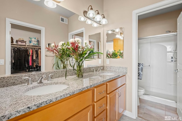 bathroom with tile patterned flooring, walk in shower, vanity, and toilet