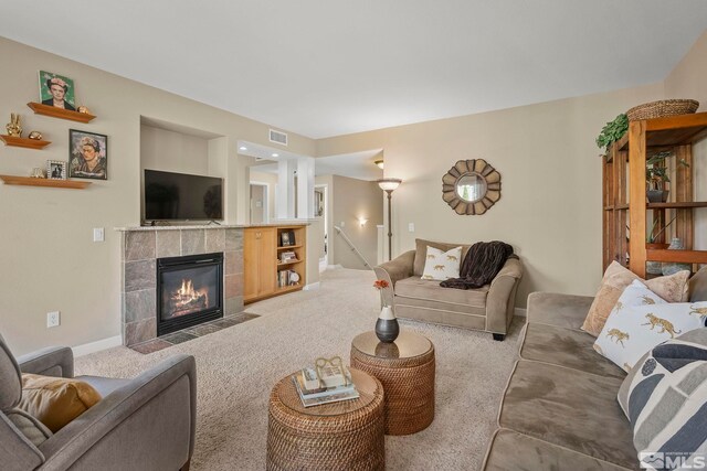 living room featuring a tiled fireplace and carpet flooring