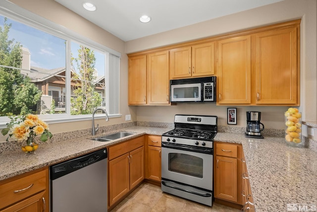 kitchen featuring stainless steel appliances, light tile patterned floors, sink, and light stone counters