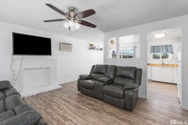 living room featuring ceiling fan, a textured ceiling, a fireplace, and hardwood / wood-style floors